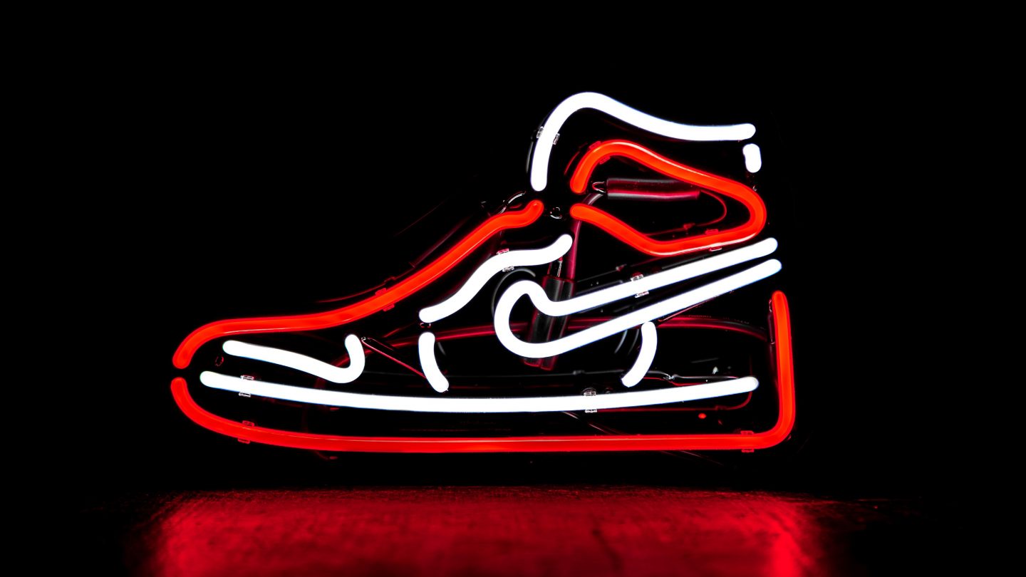 A red and white neon sign of a Nike high top trainer