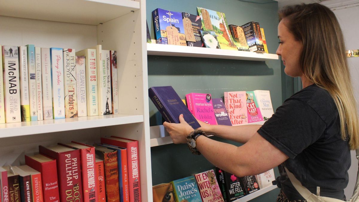 woman putting colourful books on shelf
