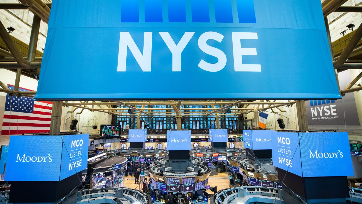 Room full of many blue screens including a large banner with 'NYSE' logo