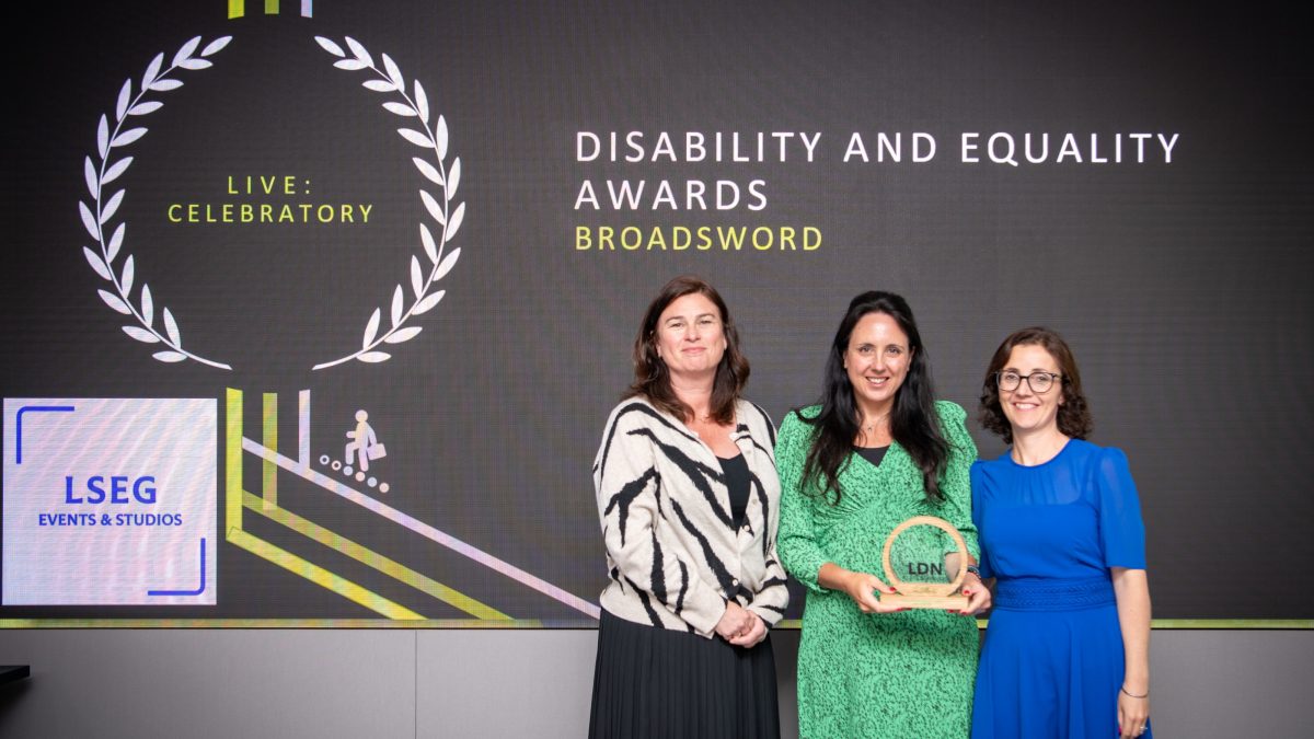 three women on stage with an award