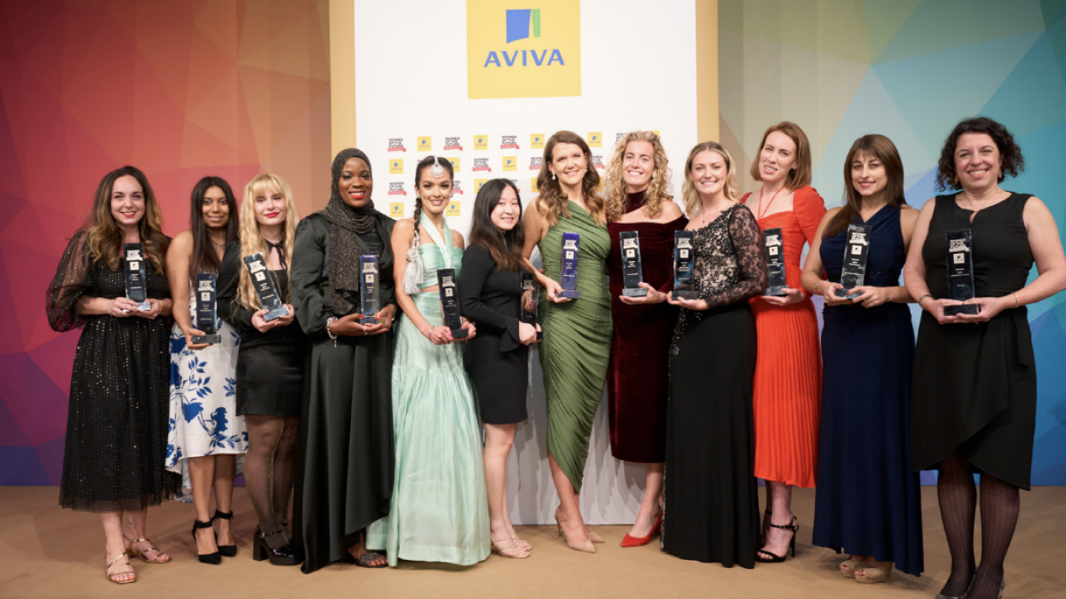Group of women in long dresses smiling and holding awards