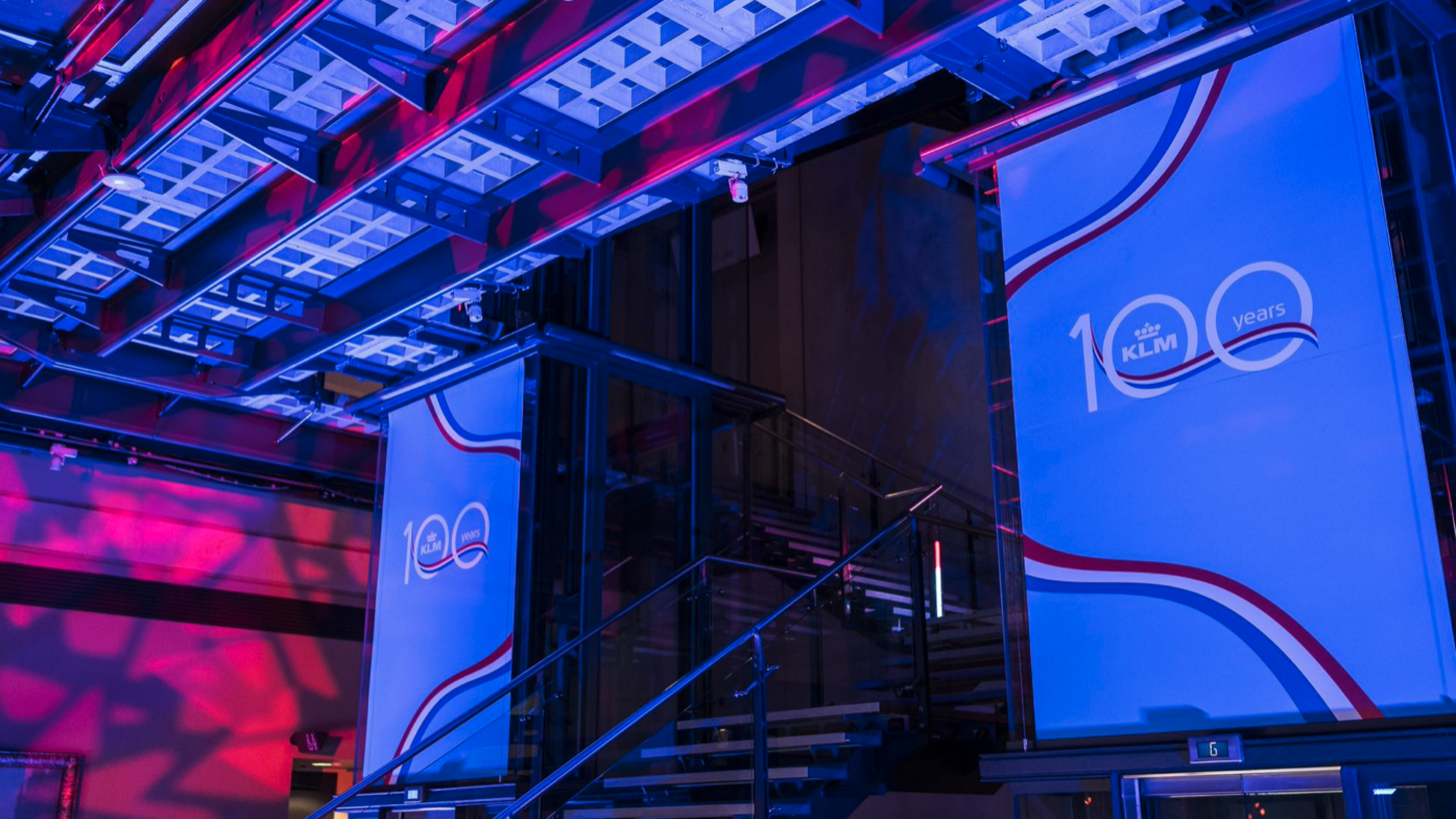 Staircase with floor to ceiling blue banners with a 100 logo on