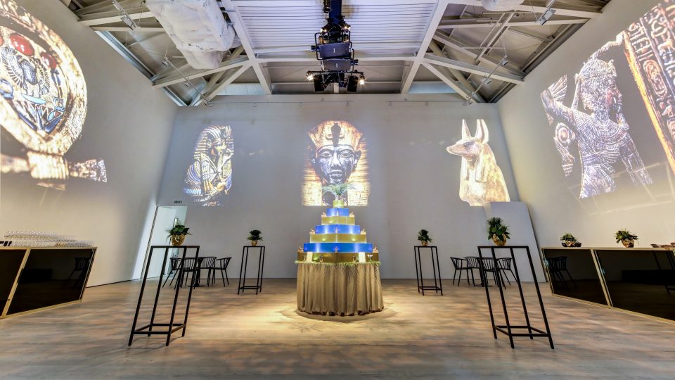 Event with projections of Tutankhamun on the walls and a blue and gold pyramid in the centre of the room