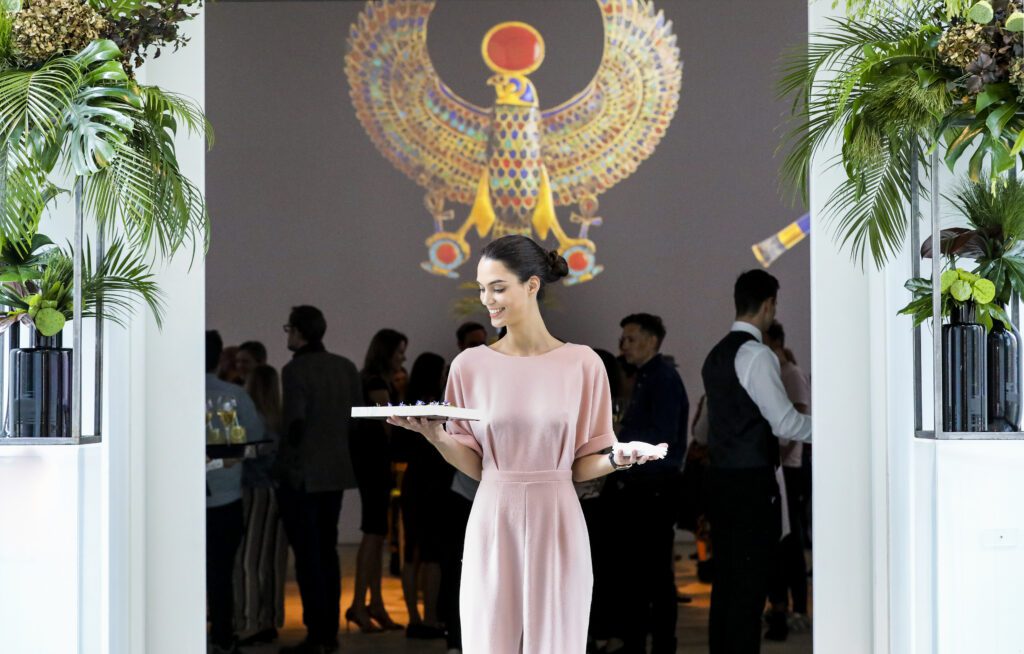 Server in doorway of gallery carrying plates of canapes